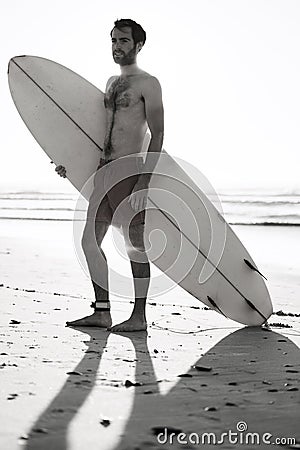 Black and white image of male surfer on the beach Stock Photo