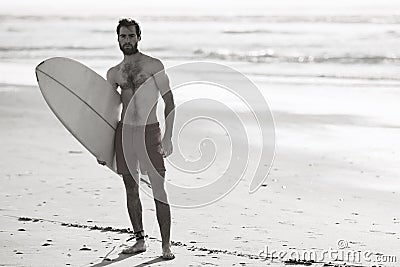 Black and white image of male surfer on the beach Stock Photo