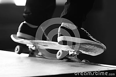 A black-white image of a man`s feet, doing a slide on a skateboard on a ramp Stock Photo