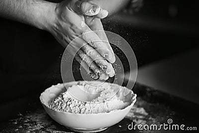 Black-white image of the process of cooking dough. The cook mixes the flour with the other ingredients on the plate and shakes the Stock Photo