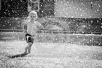 Happy Toddler Playing in the Sprinkler in the Yard Stock Photo