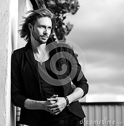 Black-white outdoor portrait of elegant long hair handsome man Stock Photo