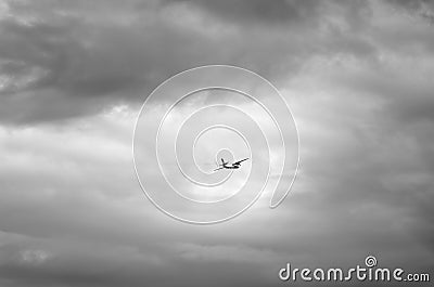 Black and white photo of a dangerous airplane flying in dark clouds Stock Photo