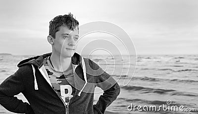 Black and white photo. Free happy young man standing on the beach feeling the warm wind looking into the distance, relaxed and Stock Photo