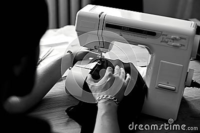 Black and white photo of Man sews clothes on sewing machine Stock Photo