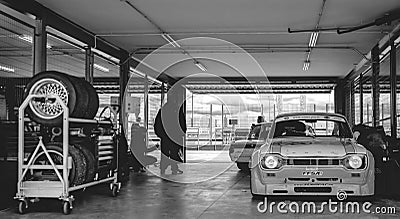 Black and white photo of the pits of a circuit with a Ford Escort 1600 RS and a 2002 BMW inside and the time board prepared in the Editorial Stock Photo