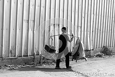 black and white photo of a seller of tofu gejrot (traditional food typical of west java) passing through a warehouse Editorial Stock Photo