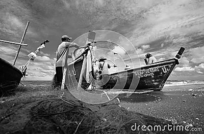 Black and white photograph of a local fisherman group on a small boat eliminating crabs, fish and marine life caught from nets Editorial Stock Photo