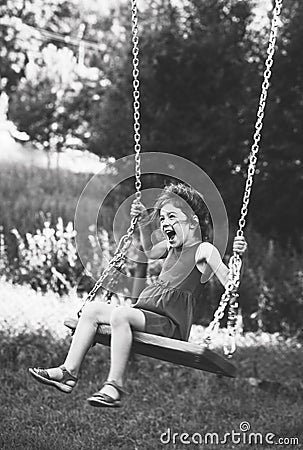 Black and white portrait of Beautiful little girl smiling on swing at summer day, Happy childhood concept. Soft focused Stock Photo