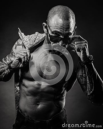 Black and white portrait brutal man with a bare torso looks from under the glasses. Studio photo. muscular body Stock Photo
