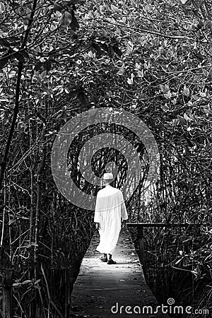 Black and white portrait of male muslim in traditional clothing walking in a mangrove forest. Fantasy of light, shadow and Stock Photo