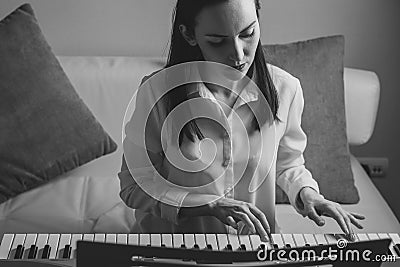 Black and white portrait of a young woman learning to play electronic piano Stock Photo