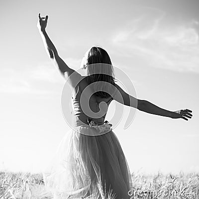 Black and white romantic beautiful young lady having fun standing in the field with hand up to the sky on outdoors background Stock Photo