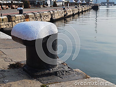 Black and white ship mooring bollard on the edge of the pier in the seaport on an sunny autumn day Stock Photo