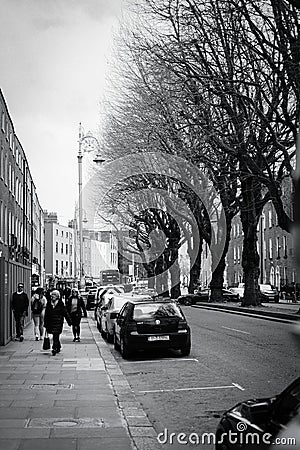 Black-and-white shot of a group of diverse people walking down the sidewalk in Dublin, Ireland Editorial Stock Photo
