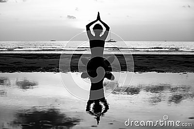 Black and white silhouette of yoga woman meditating at the sea shore. Relax. Stock Photo