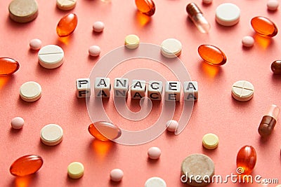 Black and white title PANACEA from white cubes on the table with tablets on coral background. Stock Photo