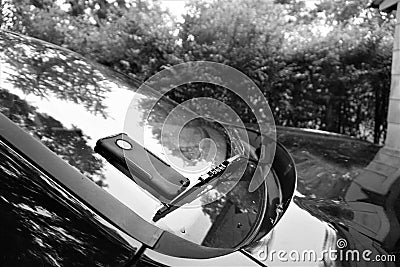 Black and white vehicle windshield with cell phone camouflaged on windshield wiper Stock Photo