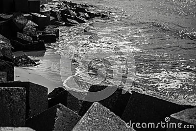 Black and white view of big stoned cubes on the sea shore. Stock Photo