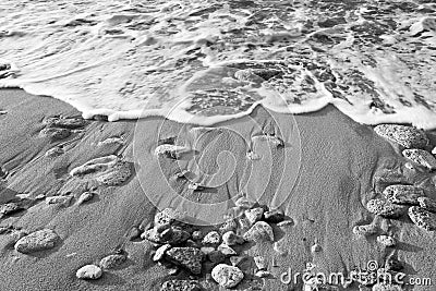 Black & White - Wave of the sea on the beach with sand and stone Stock Photo