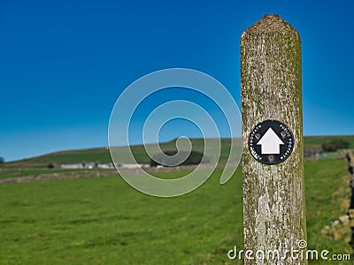 A black and white way marker on a weathered wooden post points the way on a route through the Peak District in Derbyshire, UK. Editorial Stock Photo