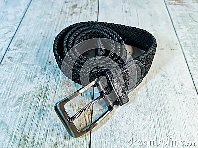 Black wicker trouser belt with a silver buckle on a wooden tabletop background Stock Photo