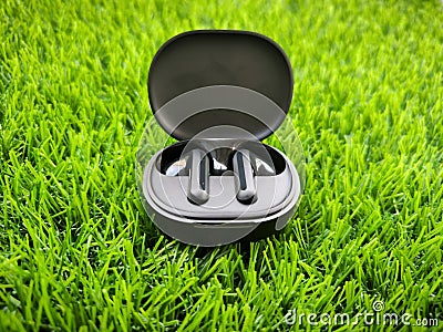 Black wireless headphones in a box on a grass background Stock Photo