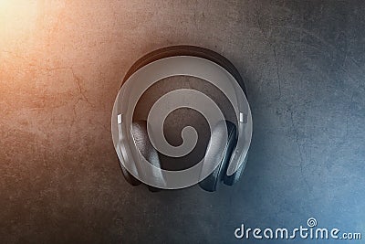 Black Wireless headphones on a black, stone background with a godly flare of blue and gold. Overhead, professional-grade Stock Photo