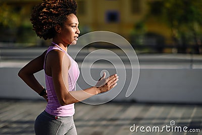 Black woman, afro hairstyle, running outdoors in urban road. Stock Photo