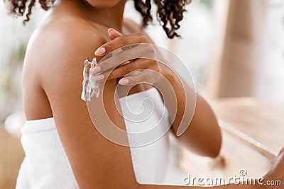 Black woman applying moisturizing body lotion on skin after shower Stock Photo