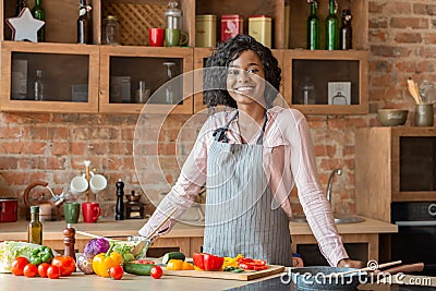 Black woman cooking healthy salad at kitchen, smiling at camera Stock Photo