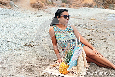 Black woman gazes at the horizon while having a picnic on the beach Stock Photo