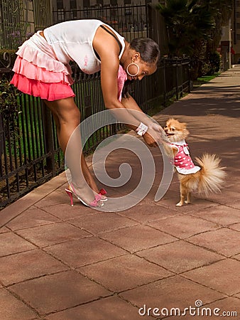 Black woman with Pomeranian Spitz (focus on dog) Stock Photo