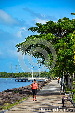 Black woman runs along the city promenade. Jogging on the ocean coast Editorial Stock Photo