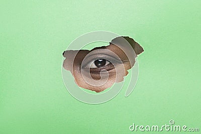 Black Woman`s Eye Without Mascara Looking Through Torn Green Paper Stock Photo