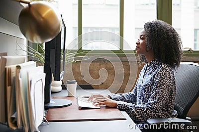 Black woman working at a computer in an office, side view Stock Photo