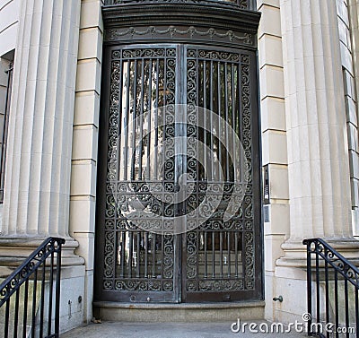 Black wrought iron door on the side of a building with a staircase leading up to it. Editorial Stock Photo