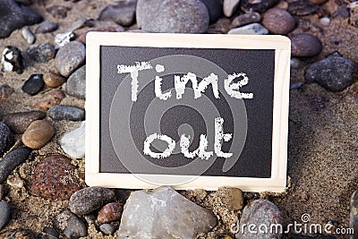 Blackboard lying between stones with the words Time Out Stock Photo