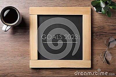 Blackboard with phrase GOALS 2023 on wooden background, flat lay Stock Photo