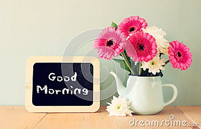 Blackboard with the phrase good morning written on it next to vase with fresh flowers Stock Photo