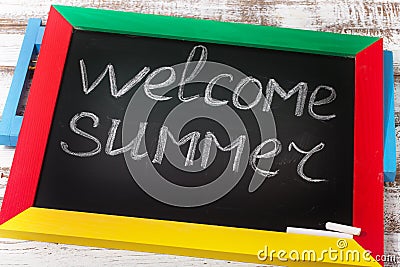 Blackboard with text it's Welcome summer on wooden deck Stock Photo