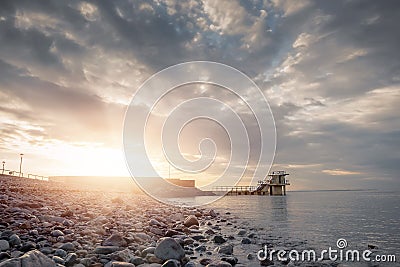 Blackrock diving board at sunrise. Salthill beach. Popular swimming spot, High tide. Sun flare, Cloudy sky. Galway city, Ireland. Stock Photo
