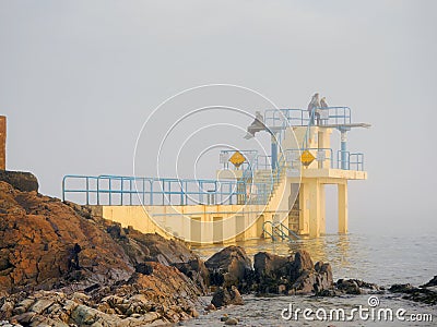 Blackrock public diving tower in Salthil area of Galway in a fog. Tourists on a top of the tower Editorial Stock Photo