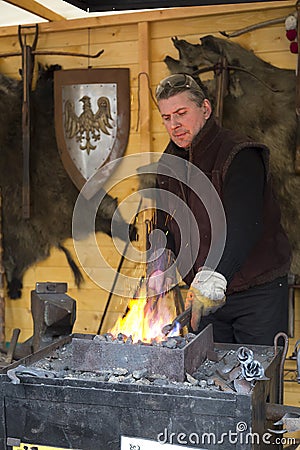 Blacksmith forging a horseshoe at the Christmas fair in Warsaw Editorial Stock Photo