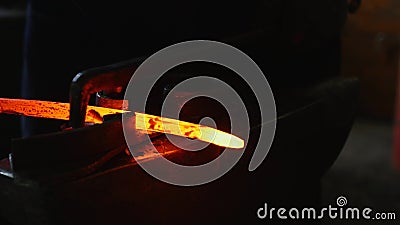 Blacksmith working with hot glowing metal, bending steel in a smithery Stock Photo