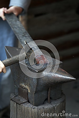 Blacksmith works the incandescent iron with anvil and hammer Stock Photo