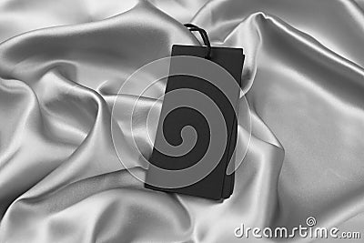 Blank black tags on silver silky fabric. Space for text Stock Photo