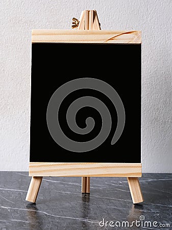 Blank black wooden menu board, chalkboard, standing over white cement wall with copy space, template, Blackboard mock up for Stock Photo