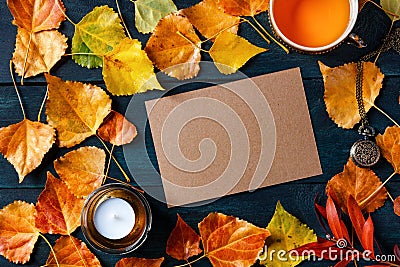 A blank brown craft greeting card or invitation with a cup of a tea, autumn leaves and a candle, an autumn stationery Stock Photo