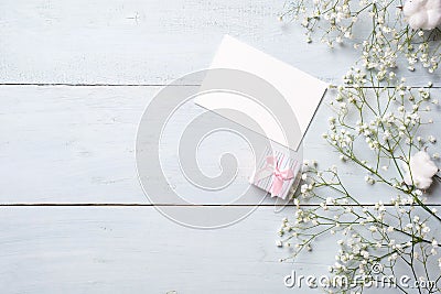 Blank card for invitation or congratulation, little gift box, bunch of gypsophila flowers on light blue wooden table. Banner mocku Stock Photo